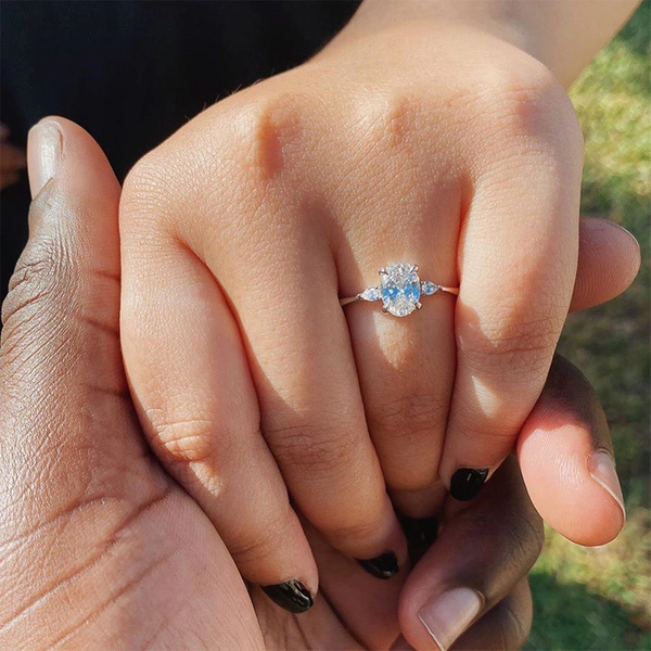 An elegant three-stone ring featuring a radiant oval center gem embraced by soft pear-cut side stones.