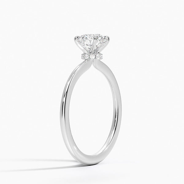 Celestia Crown radiates refined luxury, with a hidden halo of diamonds encircling the base of a dazzling round center stone in a sleek white metal setting.
