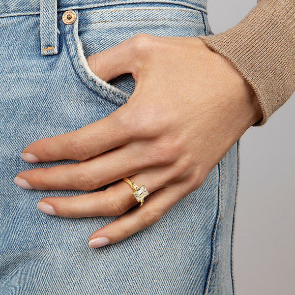 The Solmaris Crest ring showcases a commanding emerald-cut diamond framed by trapezoid side stones, exuding modern elegance and architectural beauty.